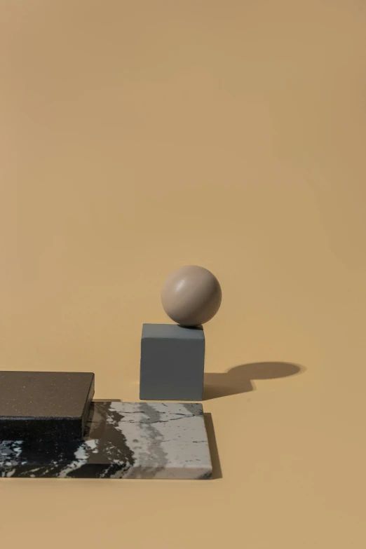 a sculpture sitting on top of a table next to a ball, an abstract sculpture, inspired by Giorgio Morandi, unsplash, taupe, detailed product image, modular, with the moon out