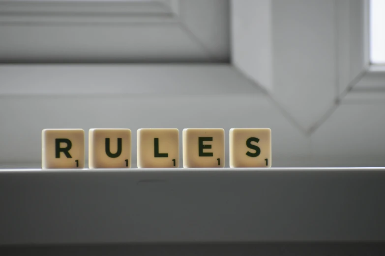 wooden blocks spelling rules on a window sill, by Daniel Lieske, pexels contest winner, on a gray background, cubicles, rubies, gaming