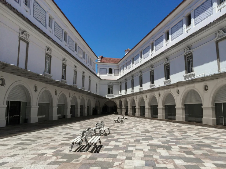 a group of benches sitting on top of a checkered floor, inspired by Dionisio Baixeras Verdaguer, pexels contest winner, quito school, white building, courtyard walkway, monumental giant palace, youtube thumbnail