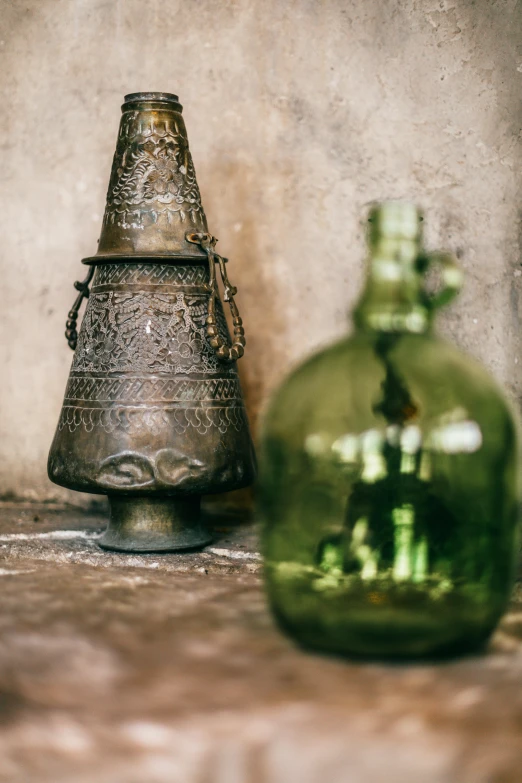 a green glass bottle sitting next to a green vase, by Adam Marczyński, trending on unsplash, renaissance, morrocan lamp, extreme intricate metal details, braziers, cone shaped