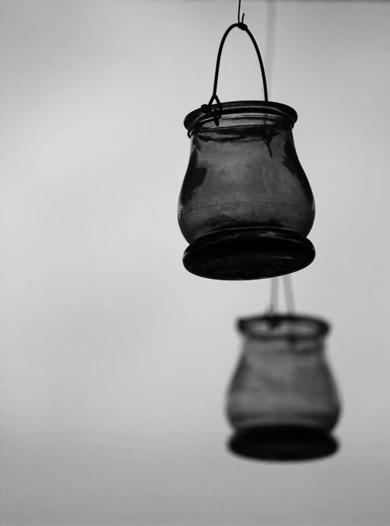 two glass jars hanging from a wire, by Rebecca Horn, cinematic. by leng jun, black & white photograph, lynn skordal, joon ahn