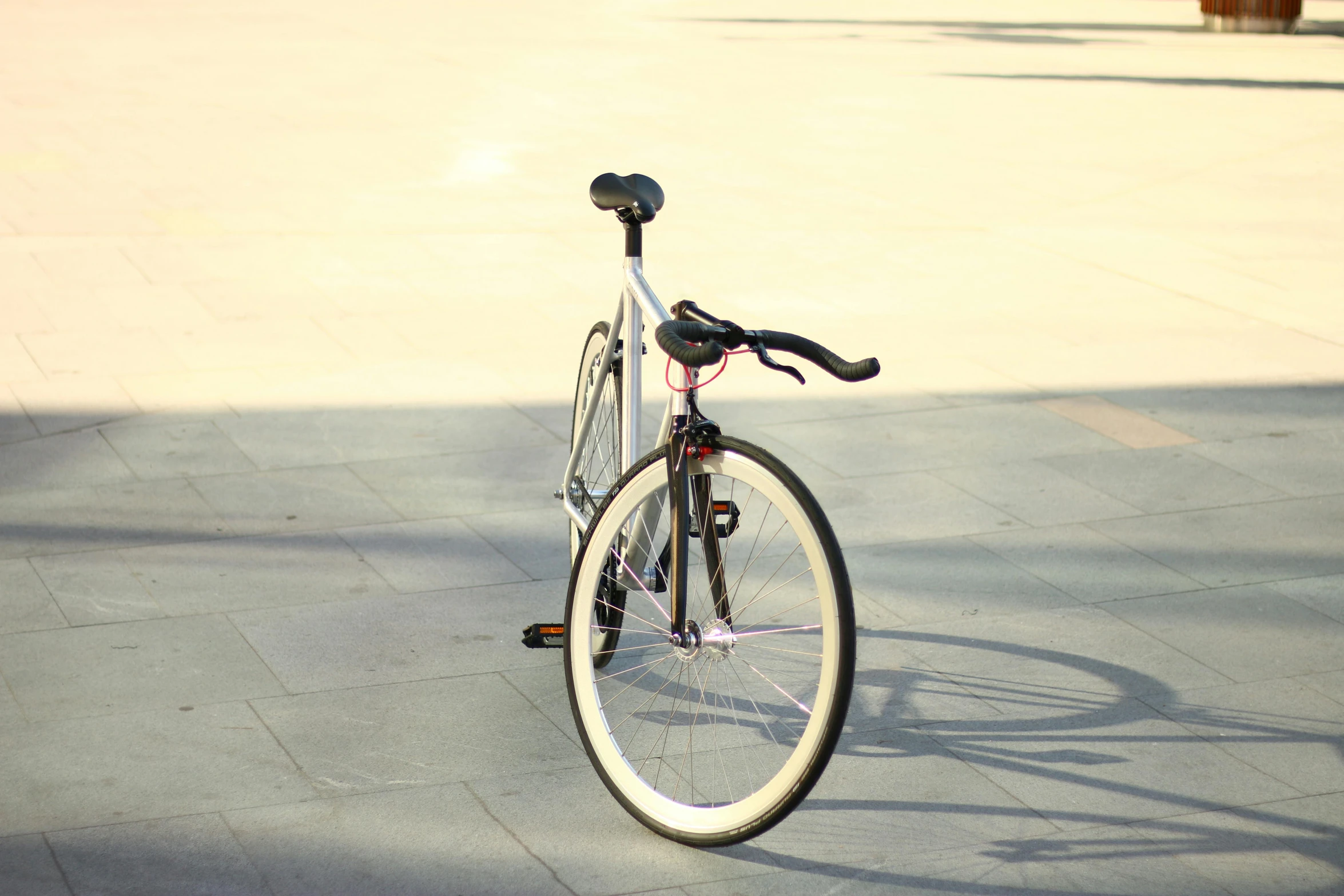 a close up of a bicycle parked on a sidewalk, by Niko Henrichon, pexels contest winner, glossy white metal, ultra hyper realistic, symmetrical rim light, sun flare