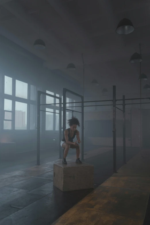 a person sitting on top of a box in a room, inspired by Elsa Bleda, pexels contest winner, realism, in a gym, dense volumetric fog, still from a music video, worried