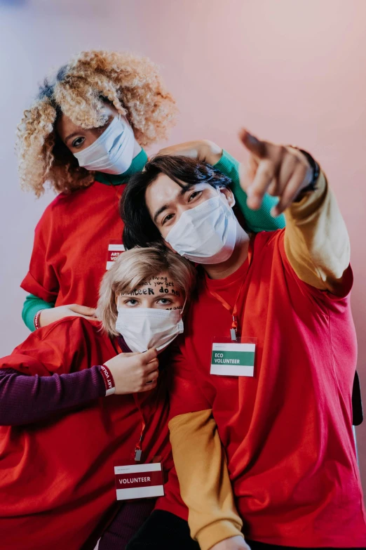 a group of people wearing face masks, a picture, trending on pexels, antipodeans, pointing at the camera, nurse, colourful clothing, red face