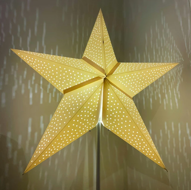 a lighted star on a stand against a wall, a stipple, pexels, light and space, yellow parasol, very crisp details, cardboard, lots of stars