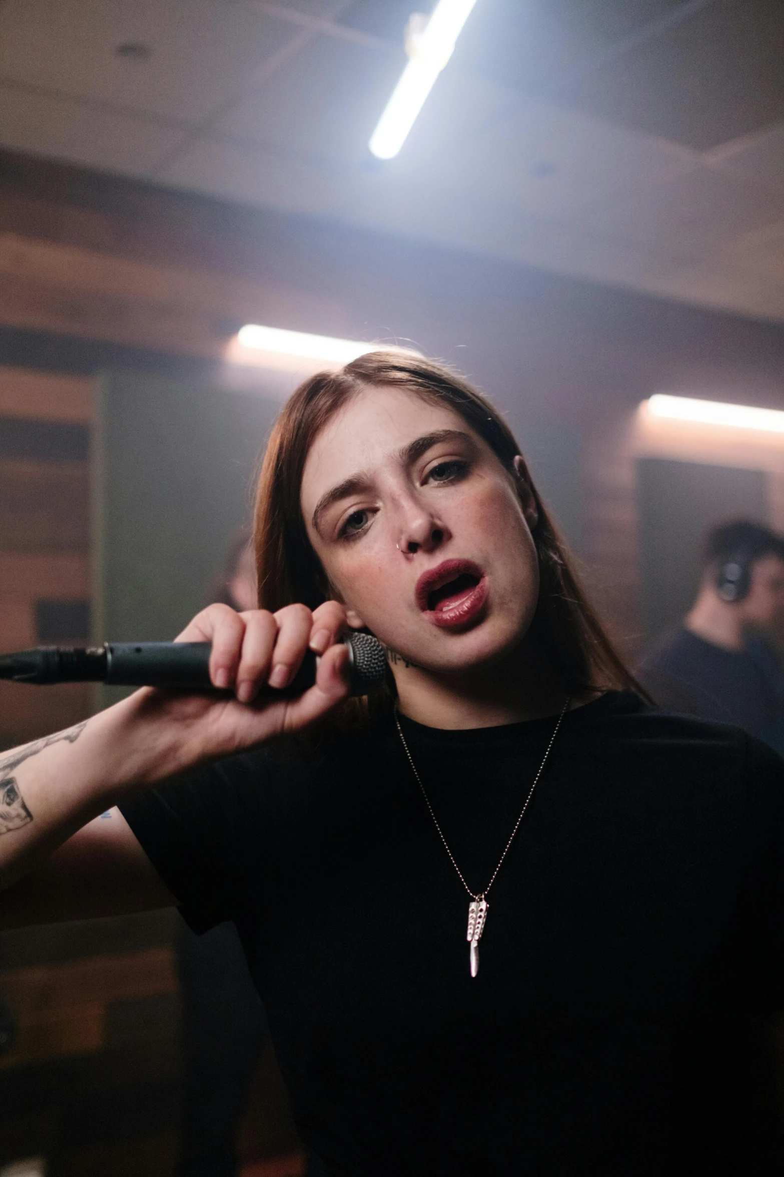 a woman holding a microphone up to her ear, an album cover, trending on pexels, realism, sansa, performing a music video, asher duran, studio photo