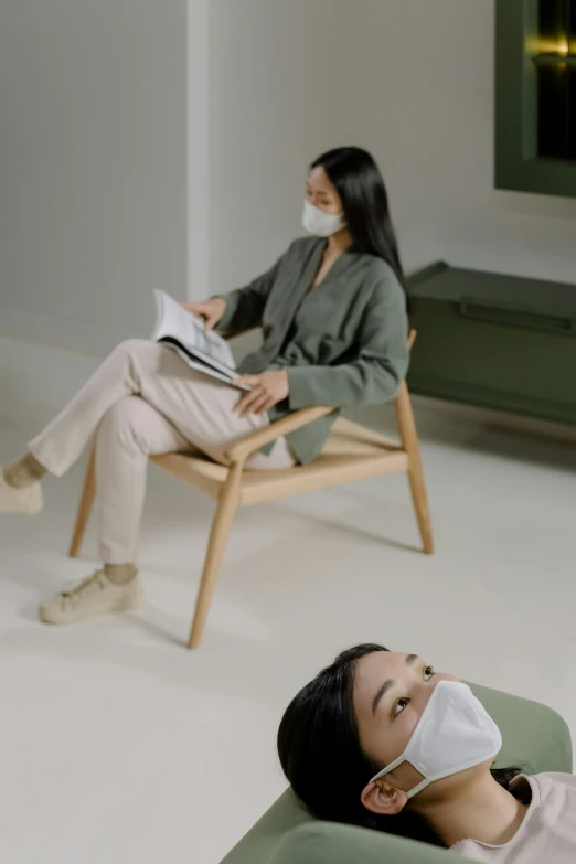 a woman sitting in a chair with a face mask on, inspired by Fei Danxu, trending on pexels, with furniture overturned, two people, jinyoung shin, green facemask