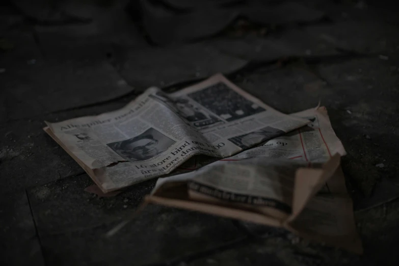 a couple of newspapers sitting on top of a wooden floor, the ground is dark and cracked, book of the dead, shot with sony alpha, background image