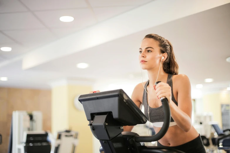 a woman on a stationary bike listening to music, pexels contest winner, figuration libre, chun li at the gym, profile image, landscape shot, thumbnail