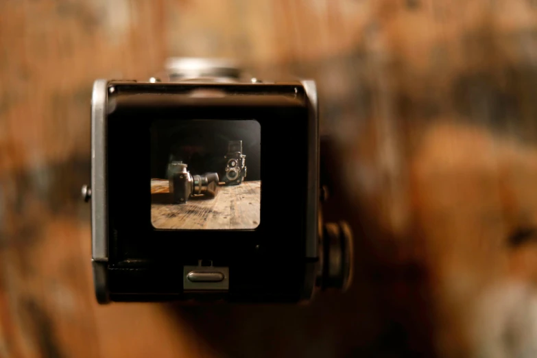 a camera sitting on top of a wooden table, inspired by Vivian Maier, unsplash, cinestill hasselblad 8 mm, wartime footage, close up to the screen, on display