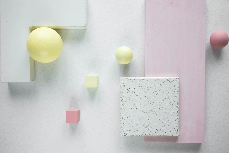 a group of objects sitting on top of a white surface, inspired by Bauhaus, plasticien, light blush, white and yellow scheme, the cube, detail texture