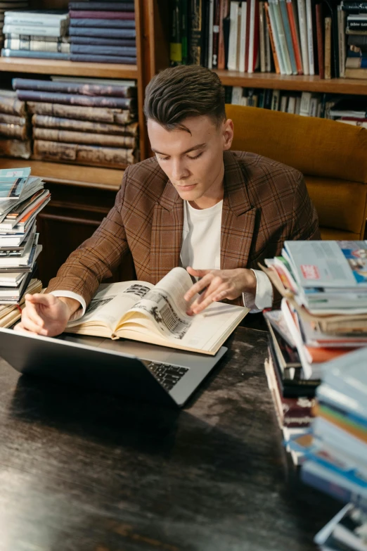 a man sitting at a desk reading a book, by Carey Morris, pexels, happening, non binary model, grand library, joe keery, inspect in inventory image