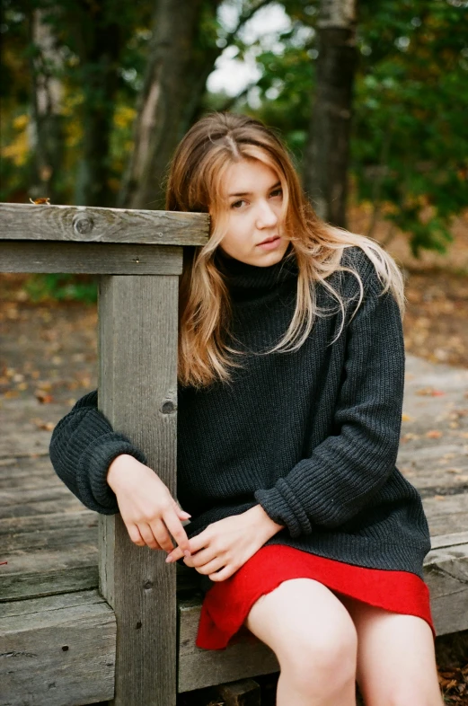 a woman sitting on a wooden bench in the woods, a portrait, trending on unsplash, fine art, wearing turtleneck, teenage, scarlet johansen, confident relaxed pose