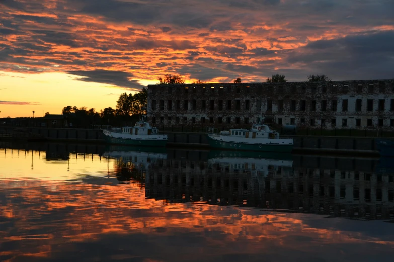 a couple of boats that are sitting in the water, by Robert Storm Petersen, pexels contest winner, auto-destructive art, explorers of the ruins at dusk, orange clouds, shipyard, iridescence reflecting