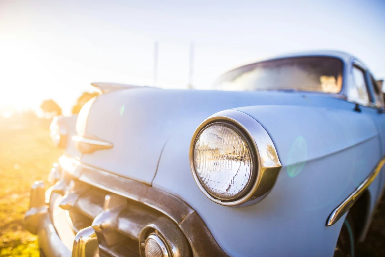 a close up of an old car in a field, a portrait, trending on unsplash, photorealism, blue headlights, perfect crisp sunlight, driving through a 1 9 5 0 s town, instagram photo