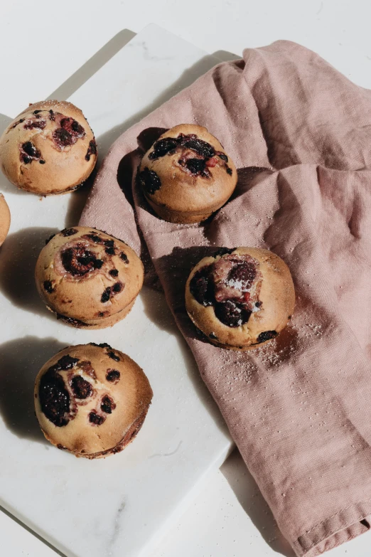 a white plate topped with muffins next to a pink napkin, by Nina Hamnett, unsplash, blueberry, brood spreading, dramatic shading, 6 pack