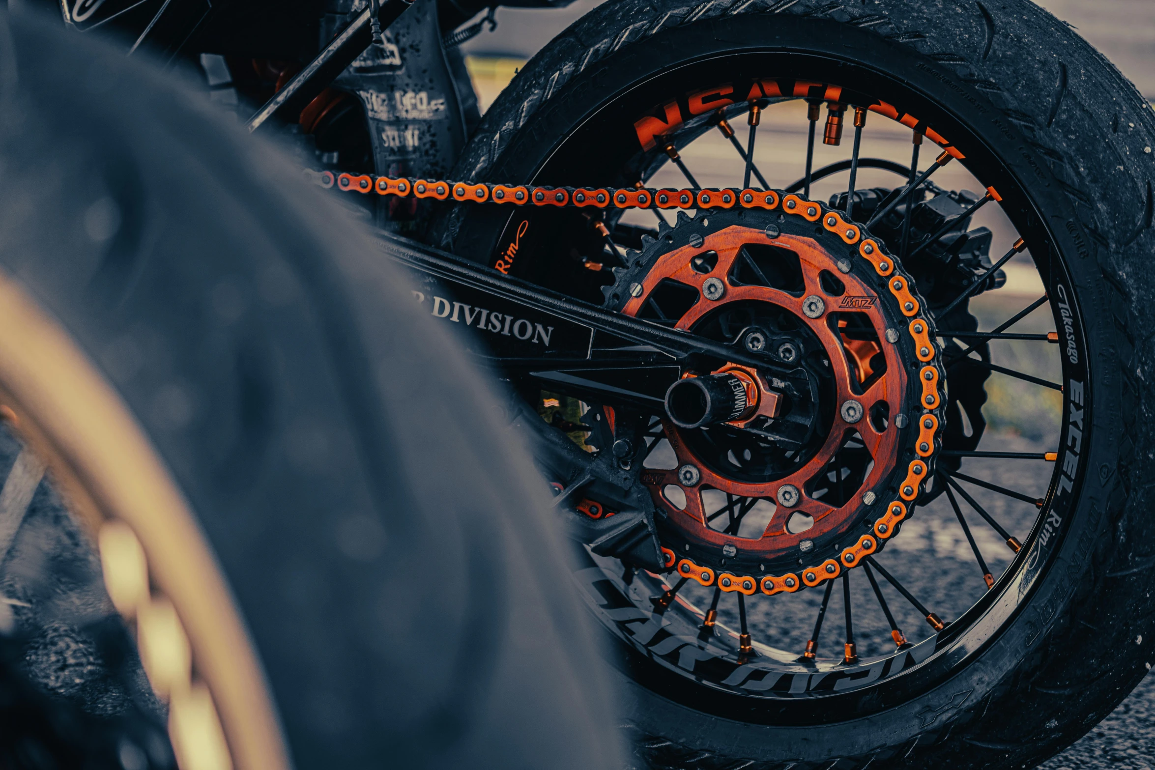 a close up of the front wheel of a motorcycle, pexels contest winner, orange and black, chains, black and red scheme, off - road