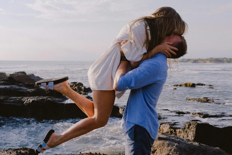 a man carrying a woman on his back by the ocean, pexels contest winner, happening, making out, standing on rocky ground, excited, alexa grace