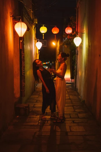 a couple standing next to each other in an alley, happening, vietnamese woman, hanging lanterns, lesbian, profile image