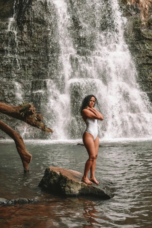 a woman standing on a rock in front of a waterfall, is wearing a swimsuit, tessa thompson inspired, vacation photo, waterfall!!!!!