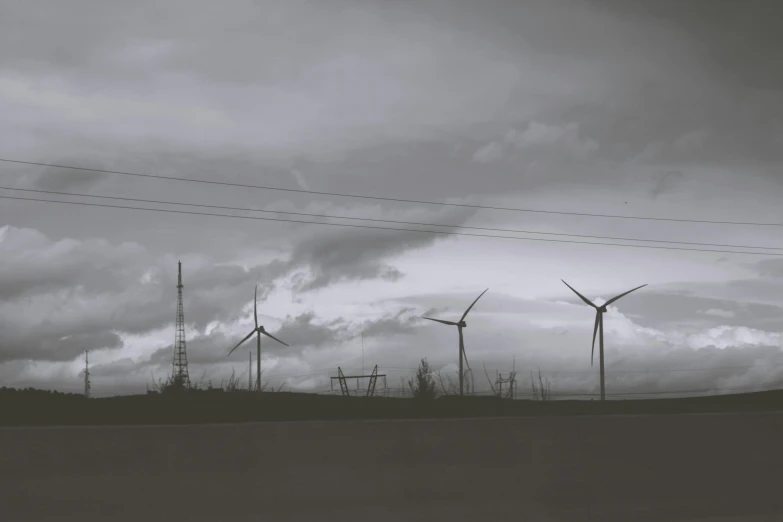 a black and white photo of wind turbines, a black and white photo, by Adam Marczyński, realism, gray sky, a green, electrical, skyline