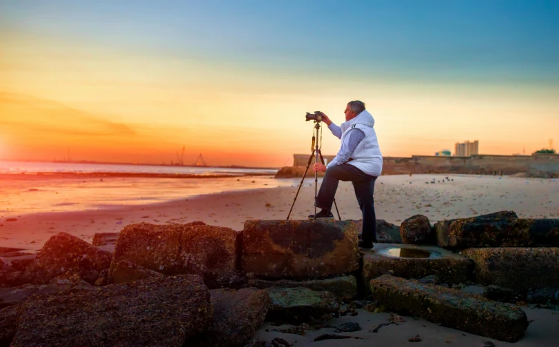 a man taking a picture of a sunset on the beach, a picture, by Eglon van der Neer, art photography, ultrawide lens”, hasselblad photography, 8k fine art photography, fujifilm”