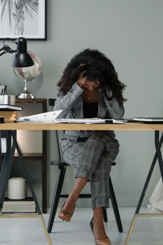 a woman sitting at a desk with her head in her hands, trending on pexels, renaissance, walking down, two exhausted, no color, sitting down casually