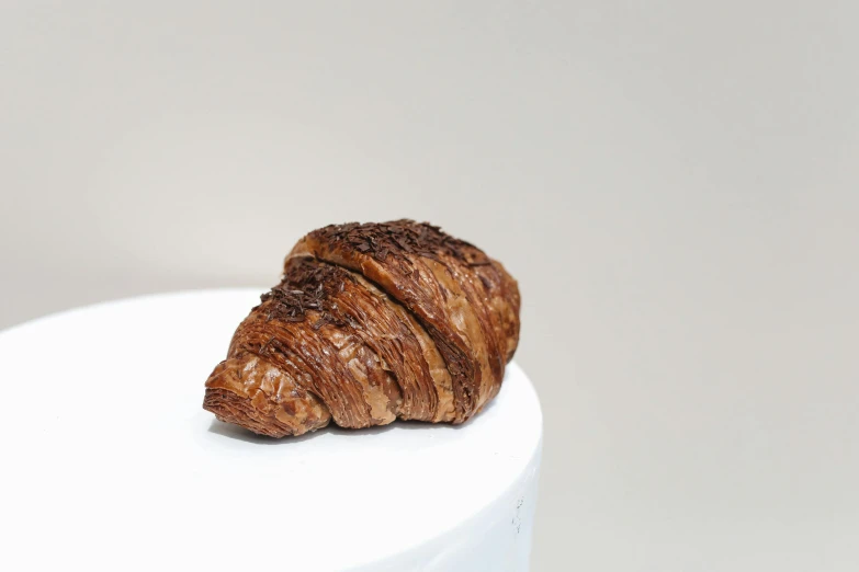 a croissant sitting on top of a white cake, a portrait, unsplash, fully chocolate, side front view, vine twist, miniature product photo