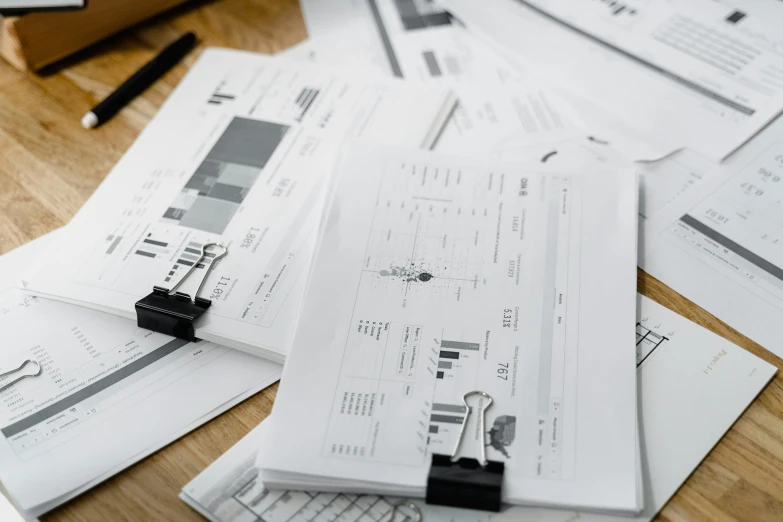 a pile of papers sitting on top of a wooden table, charts, multiple details, thumbnail, digital image