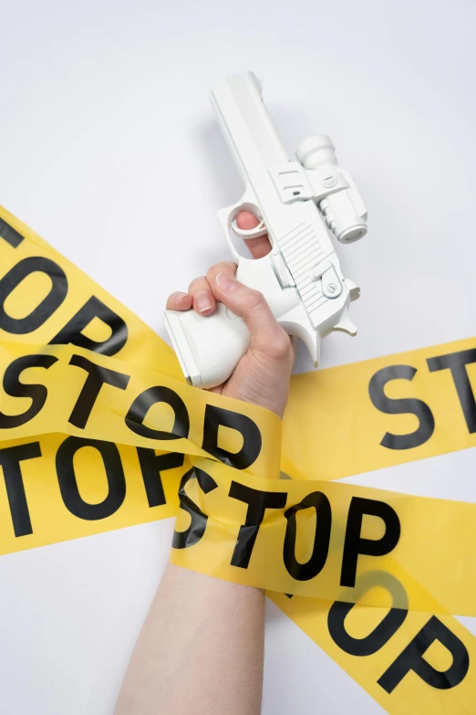 a close up of a person holding a gun, an album cover, by Andrew Stevovich, shutterstock, stop sign, police tape, airsoft gun, story