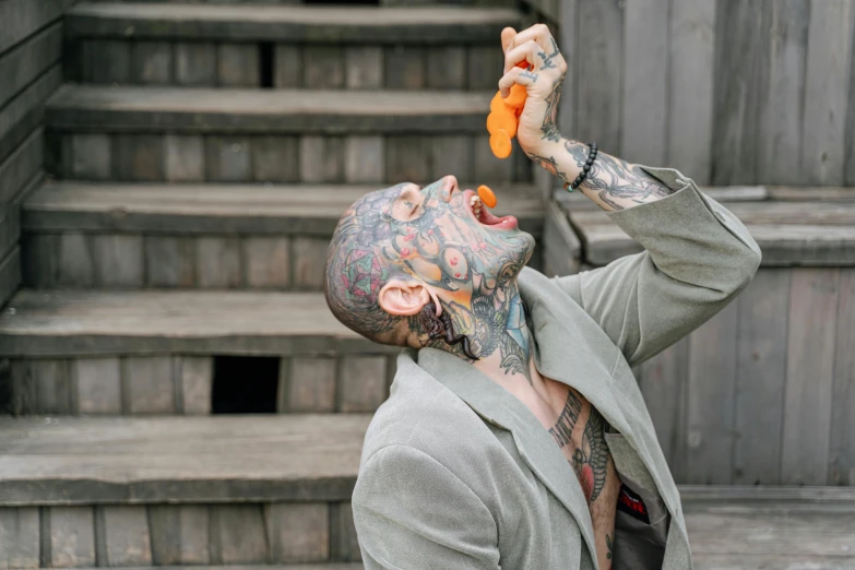 a man with tattoos on his face eating a carrot, pexels contest winner, bubble head, performance, shaved temple, actors