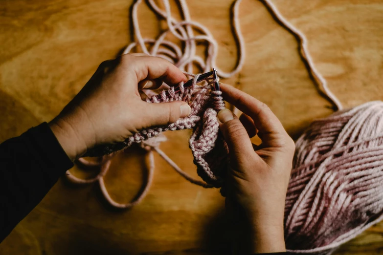 a person knitting a ball of yarn on a table, trending on pexels, webbing, samdoesarts, avatar image, crochet skin