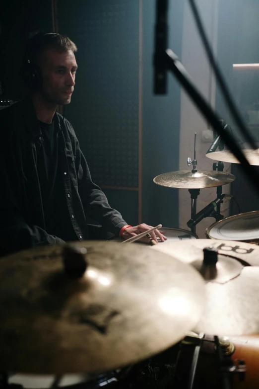 a man that is sitting in front of a drum, greg rutkowski. cinematic, studio backlight, as well as scratches, lachlan bailey