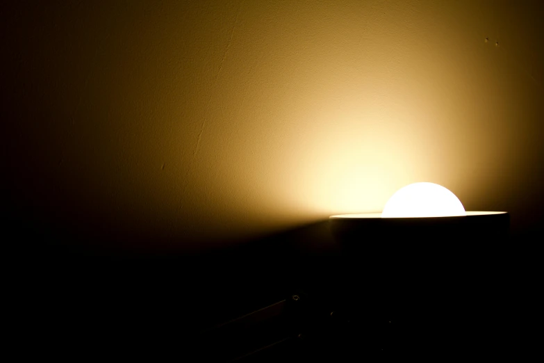a close up of a light in a dark room, an album cover, flickr, light and space, sun at dawn, warm yellow lighting, balanced lighting, dingy lighting