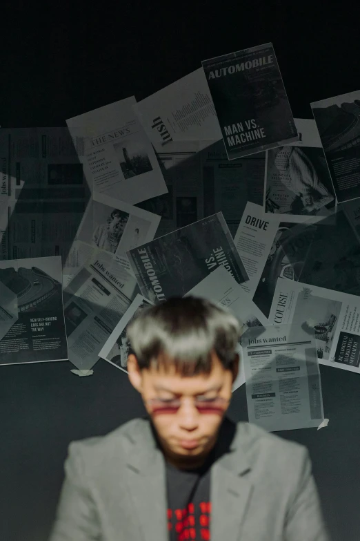 a man standing in front of a pile of papers, an album cover, by Attila Meszlenyi, pexels contest winner, detailed face of a asian boy, 15081959 21121991 01012000 4k, reading the newspaper, futuristic