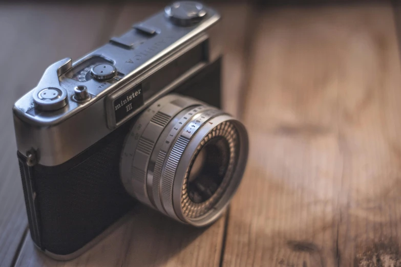 a camera sitting on top of a wooden table, a picture, by Adam Marczyński, fan favorite, vintage soft grainy, medium format, cute photograph