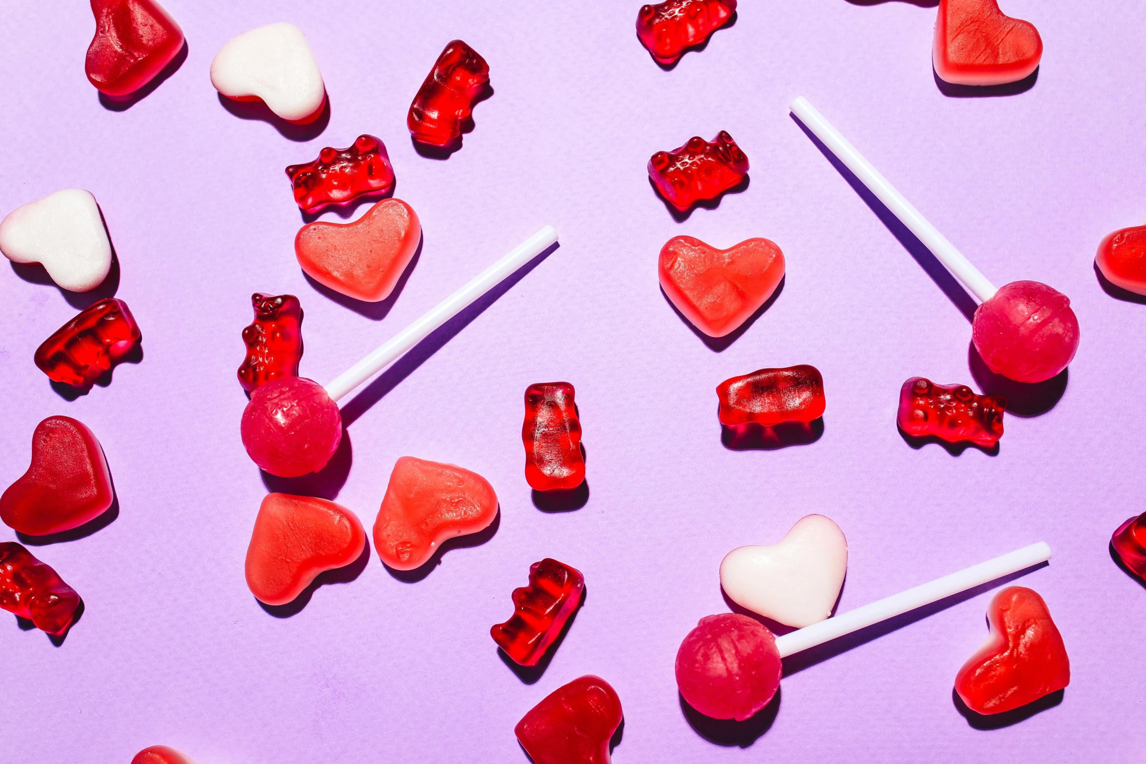 a bunch of candies sitting on top of a purple surface, by Julia Pishtar, trending on pexels, red hearts, gummy bear, an ewok eating a lollipop, profile image