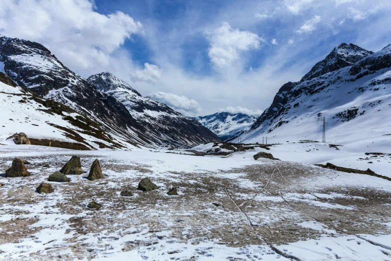 a group of rocks sitting on top of a snow covered slope, by Werner Andermatt, pexels contest winner, the middle of a valley, tent camp in foreground, snowy italian road, high quality product image”