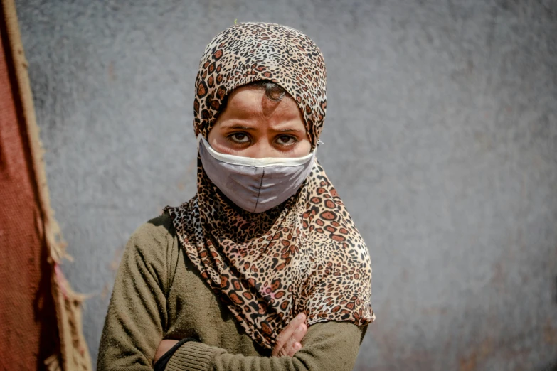 a woman wearing a face mask standing in front of a wall, hurufiyya, 5 years old, covered in bandages, illustration »