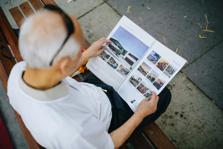 a man sitting on a bench reading a magazine, a picture, by Lee Loughridge, unsplash contest winner, modernism, chinese heritage, architect studio, an elderly, pictured from the shoulders up