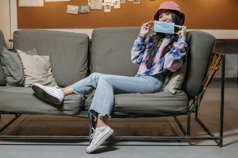 a woman sitting on a couch reading a book, trending on pexels, graffiti, surgical mask covering mouth, blue jeans and grey sneakers, avatar image, ulzzang