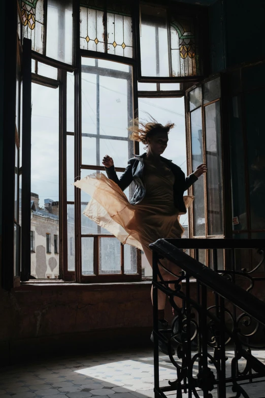 a woman that is standing in front of a window, inspired by Anka Zhuravleva, pexels contest winner, arabesque, jumping towards viewer, golden hair blowing the wind, ( ( theatrical ) ), coming down the stairs