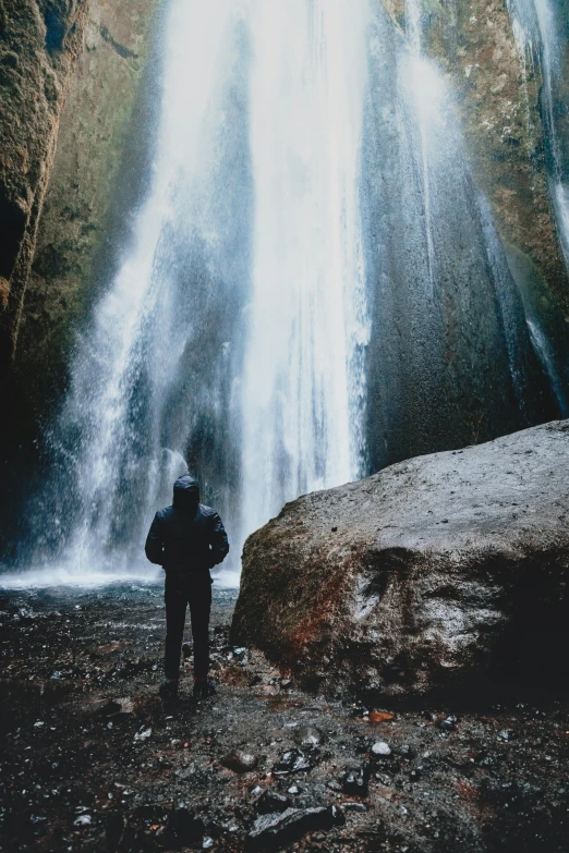 a person standing in front of a waterfall, by Jesper Knudsen, unsplash contest winner, renaissance, religion, rugged, ground level shot, natural lights