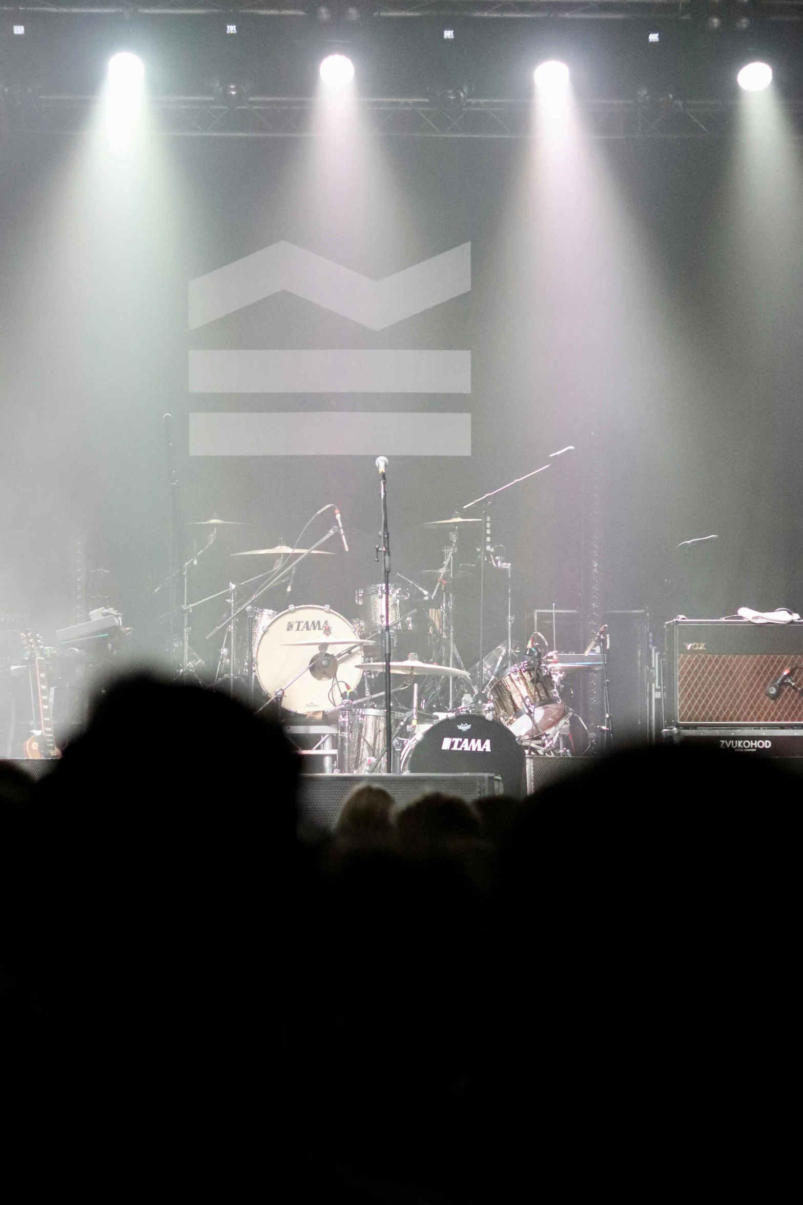 a group of people that are standing in front of a stage, an album cover, inspired by Justin Currie, flickr, drum set, zoomed in shots, soundwave, (mist)