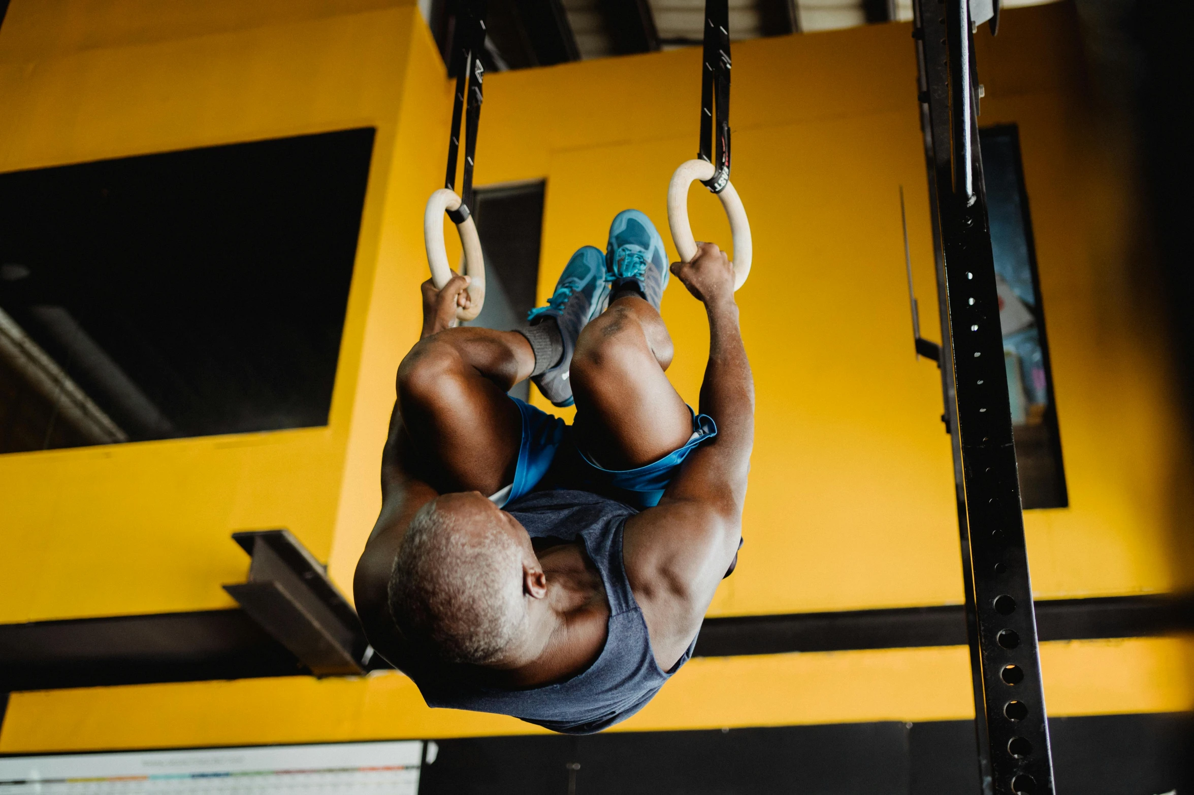 a man hanging upside down on rings in a gym, by Matija Jama, pexels contest winner, hurufiyya, 🦩🪐🐞👩🏻🦳, avatar image, emmanuel shiru, bulky build