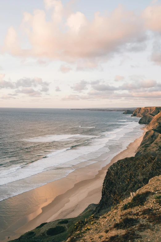 a man standing on top of a cliff next to the ocean, which shows a beach at sunset, coastal cliffs, flatlay, omaha beach