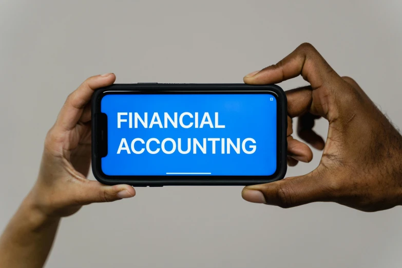 a person holding up a smart phone with the word financial accounting on it, a photo, unsplash, conceptual art, 15081959 21121991 01012000 4k, three fourths view, paul barson, a person standing in front of a