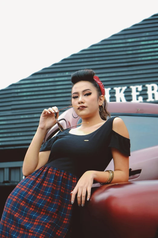 a woman leaning on the hood of a car, inspired by Rudy Siswanto, pexels contest winner, lowbrow, plaid skirt, official screenshot, rockabilly, wearing black tshirt