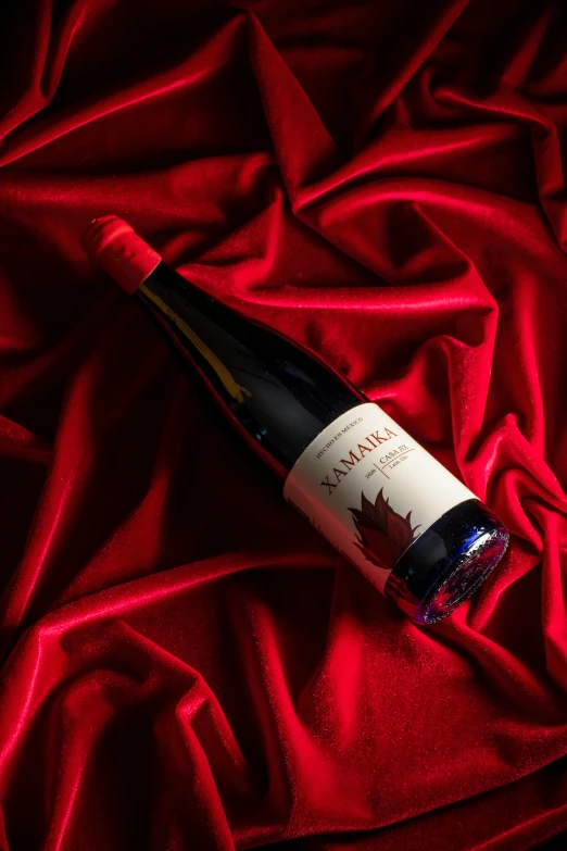 a bottle of wine sitting on top of a red cloth, kanamemo, maple syrup highlights, glowing crimson head, larapi