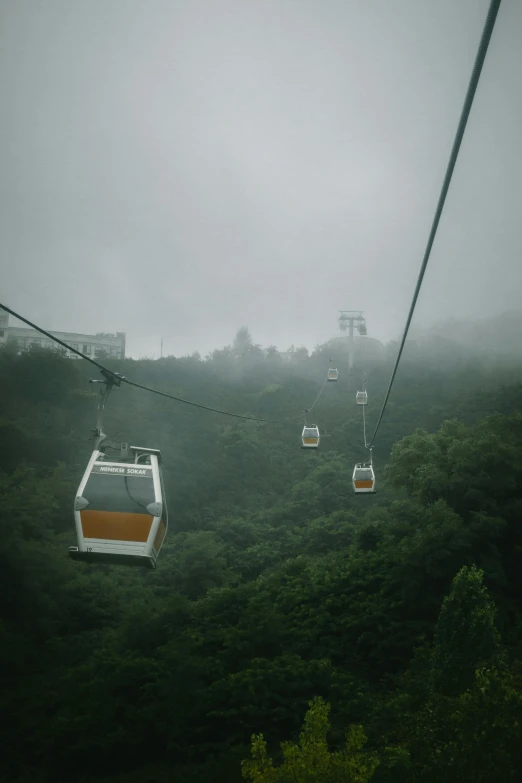 a cable car sitting on top of a lush green hillside, inspired by Zhang Kechun, unsplash, fantastic realism, overcast!!!, low quality photo, rainy, paul barson